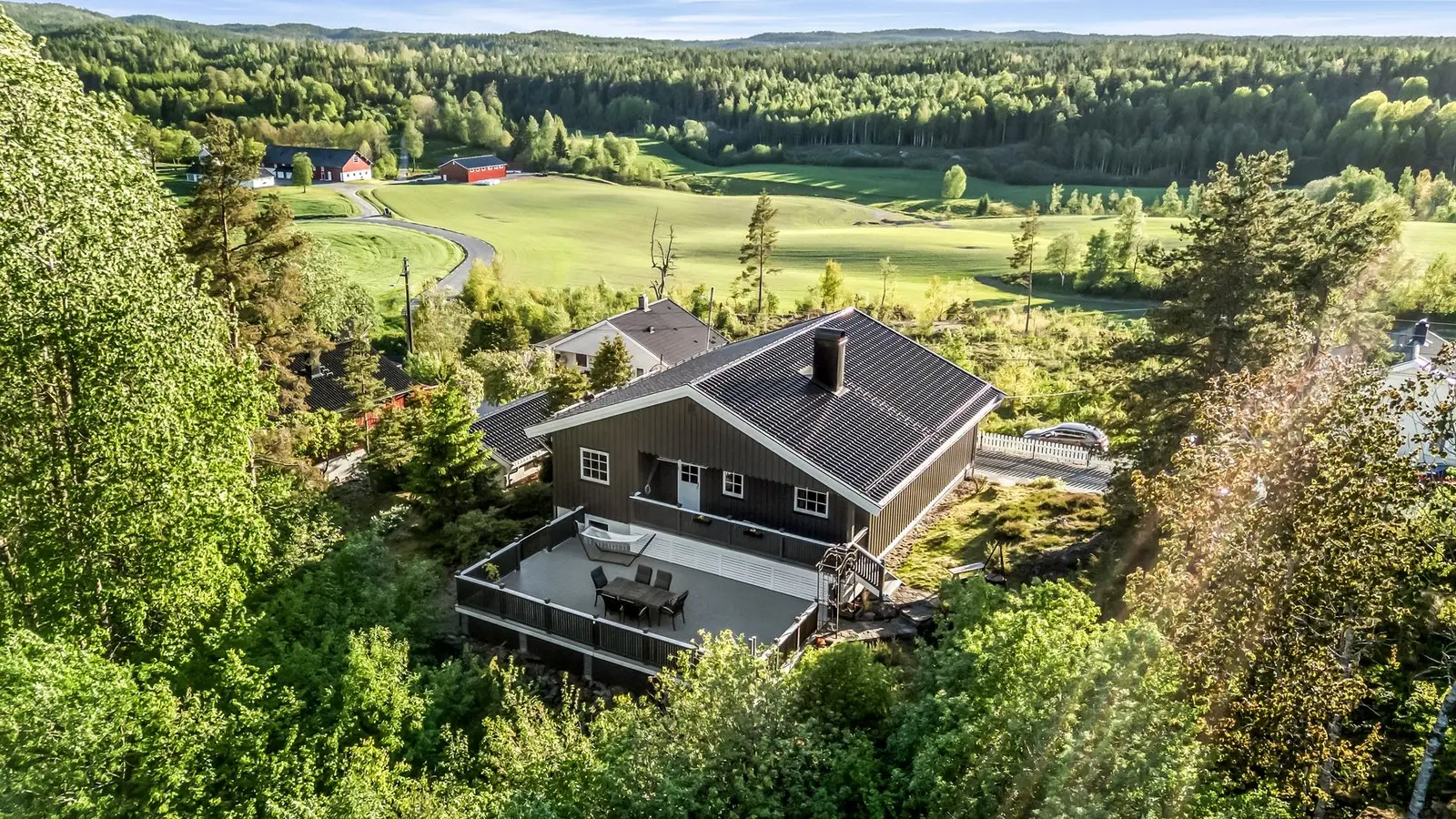 Skjermet og koselig sone på baksiden av huset som er omkranset av skog