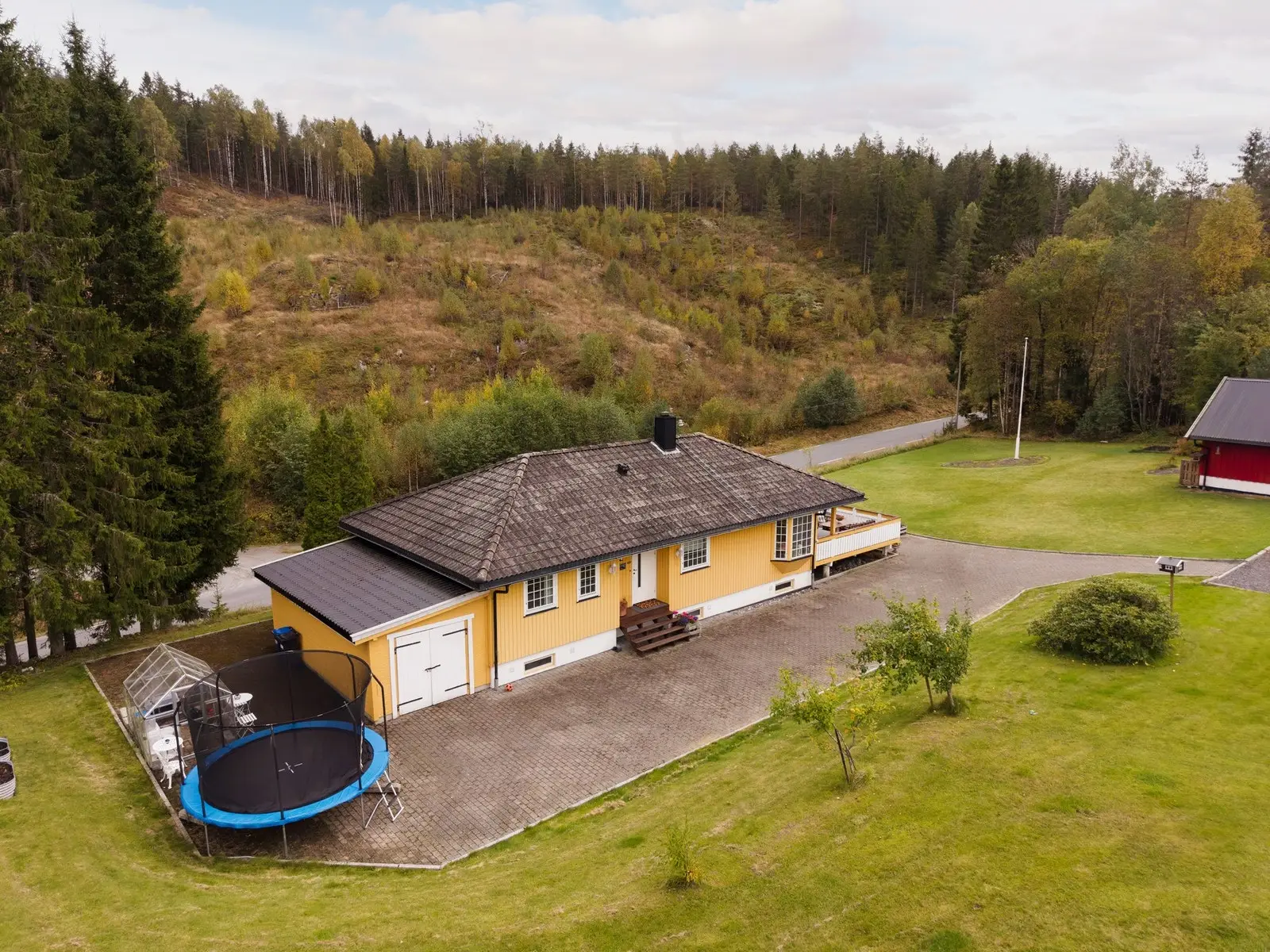 Hovedhuset har steinlagt gårdsplass på både oversiden og nedsiden av boligen.